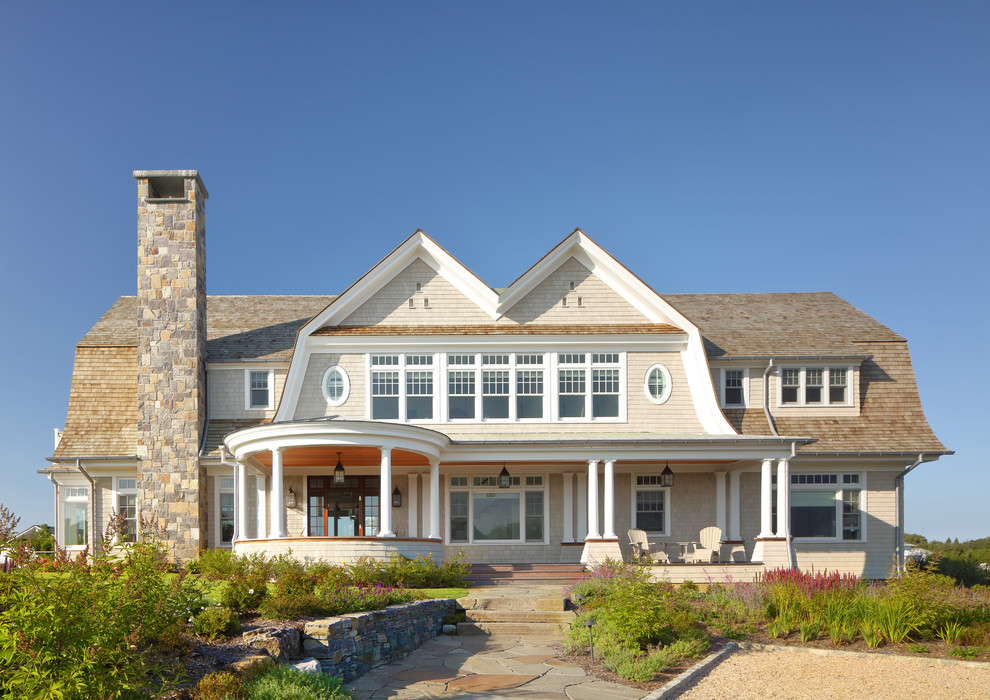 Diseño de fachada de casa beige costera de dos plantas con revestimiento de madera, tejado a doble faldón y tejado de teja de madera