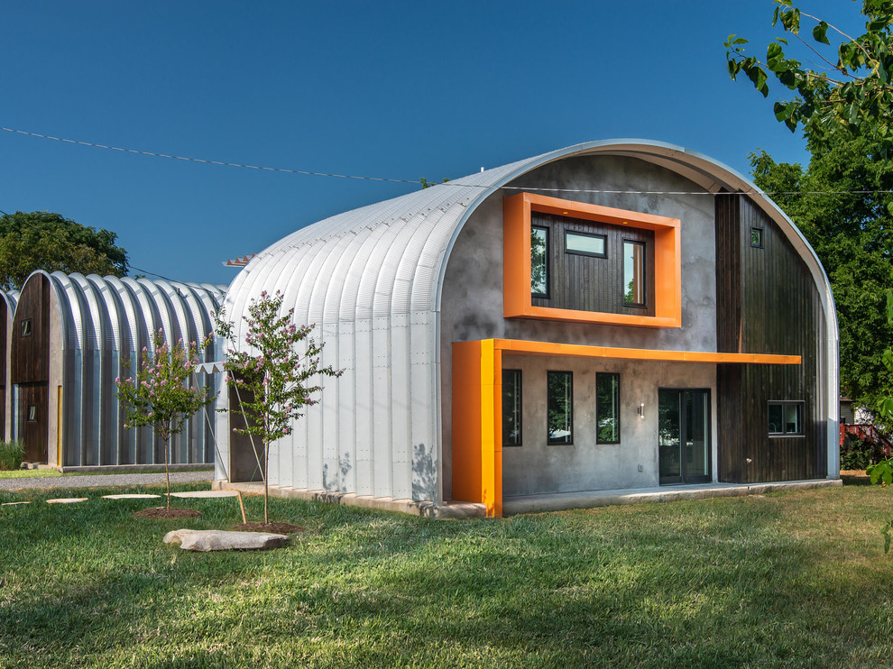 Inredning av ett industriellt mellanstort oranget hus, med två våningar, metallfasad och tak i metall