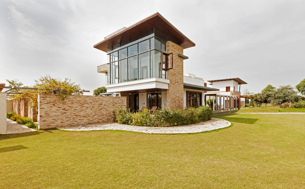 Diseño de fachada de casa beige contemporánea de dos plantas con revestimiento de piedra y tejado plano