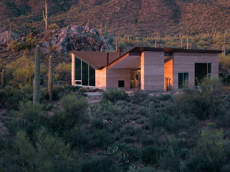 На фото: частный загородный дом в стиле модернизм с облицовкой из самана, крышей-бабочкой и металлической крышей
