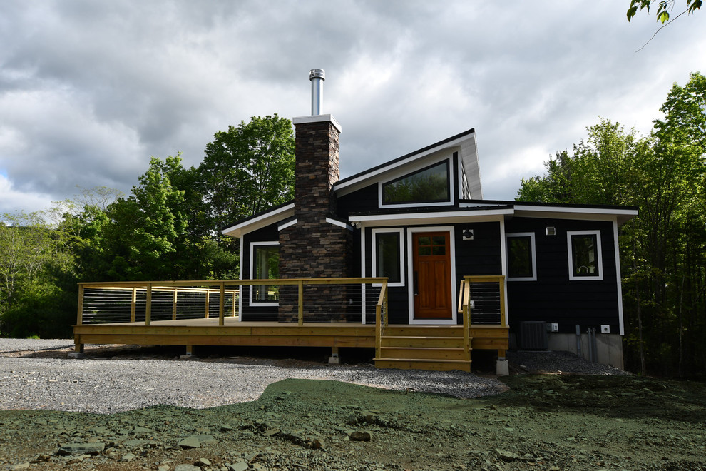 Cette photo montre une façade de maison noire rétro en bois de taille moyenne et de plain-pied avec un toit en appentis et un toit en métal.