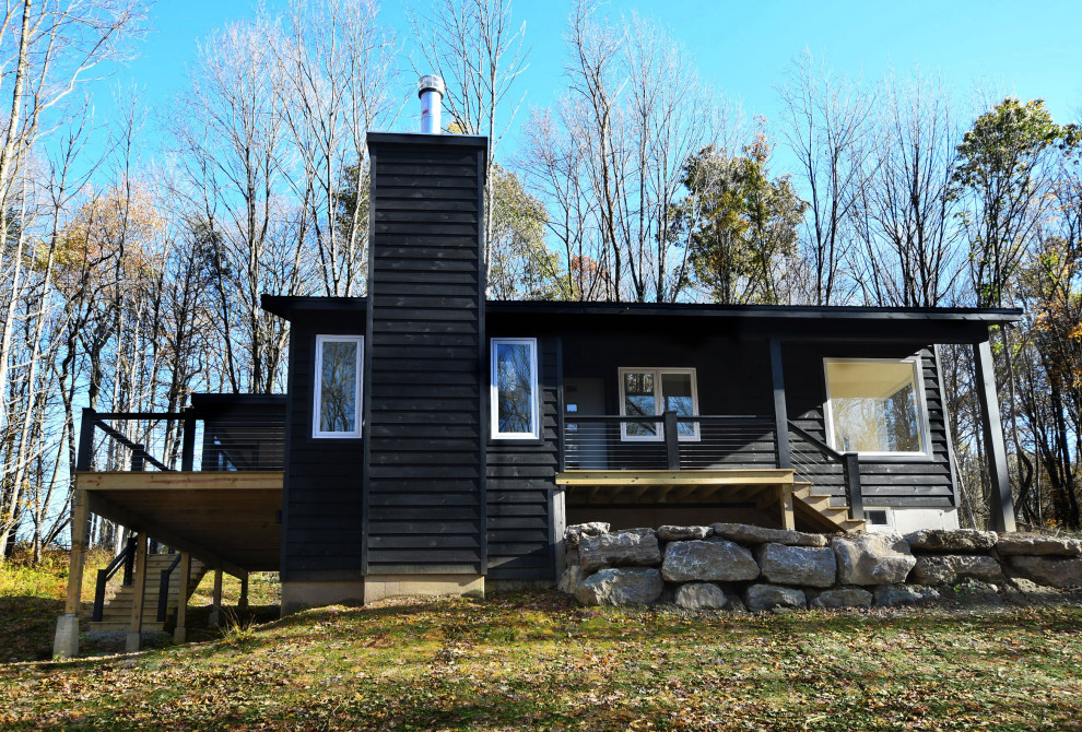 На фото: одноэтажный, деревянный, черный частный загородный дом среднего размера в стиле ретро с односкатной крышей и металлической крышей с