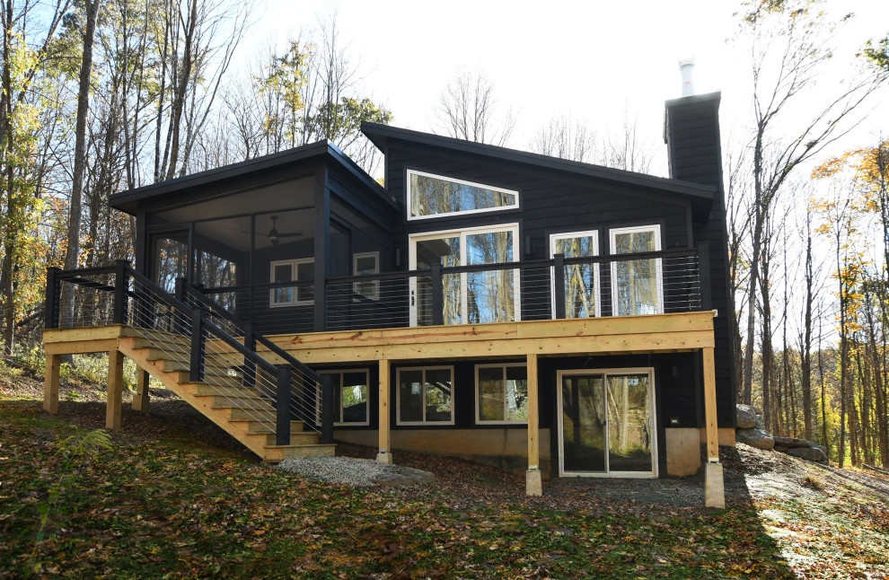 На фото: одноэтажный, деревянный, черный дом среднего размера в стиле ретро с односкатной крышей с