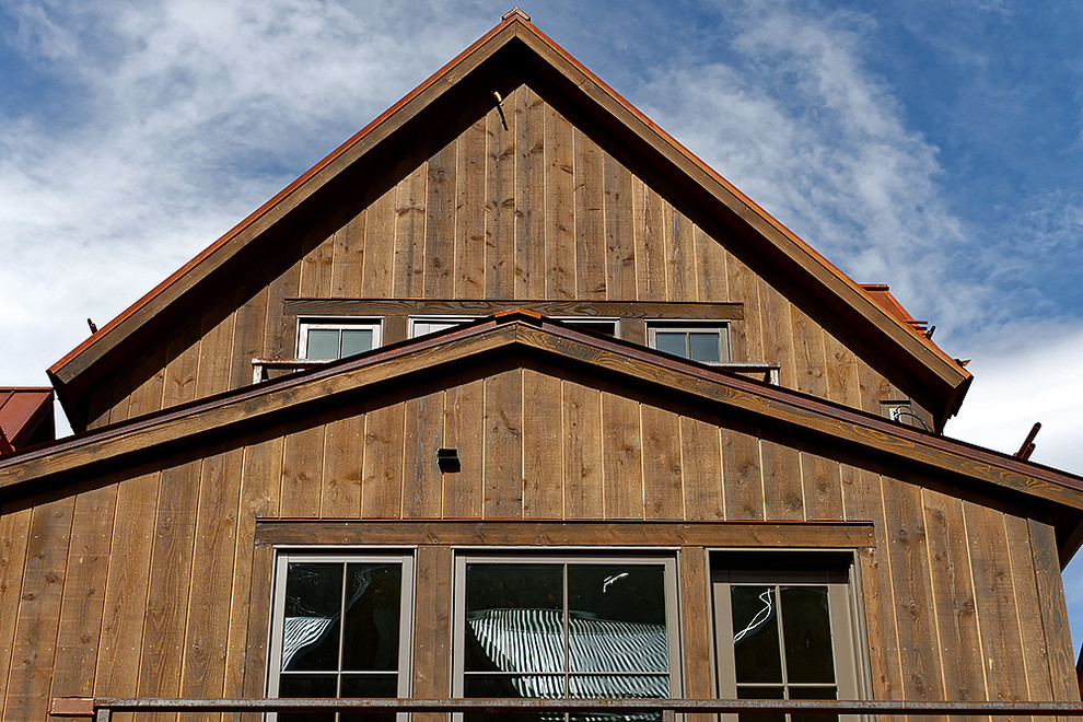 Immagine della facciata di una casa rustica a due piani con rivestimento in legno