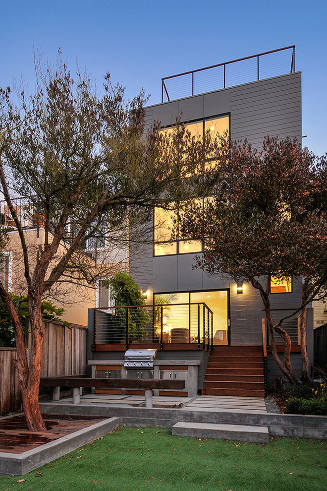Diseño de fachada gris actual de tamaño medio de tres plantas con revestimiento de aglomerado de cemento y tejado plano