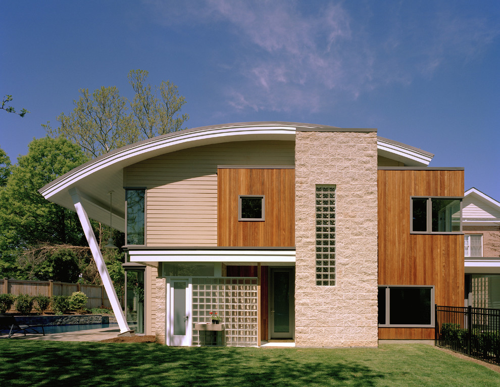 This is an example of a medium sized and beige modern two floor house exterior in DC Metro with wood cladding.