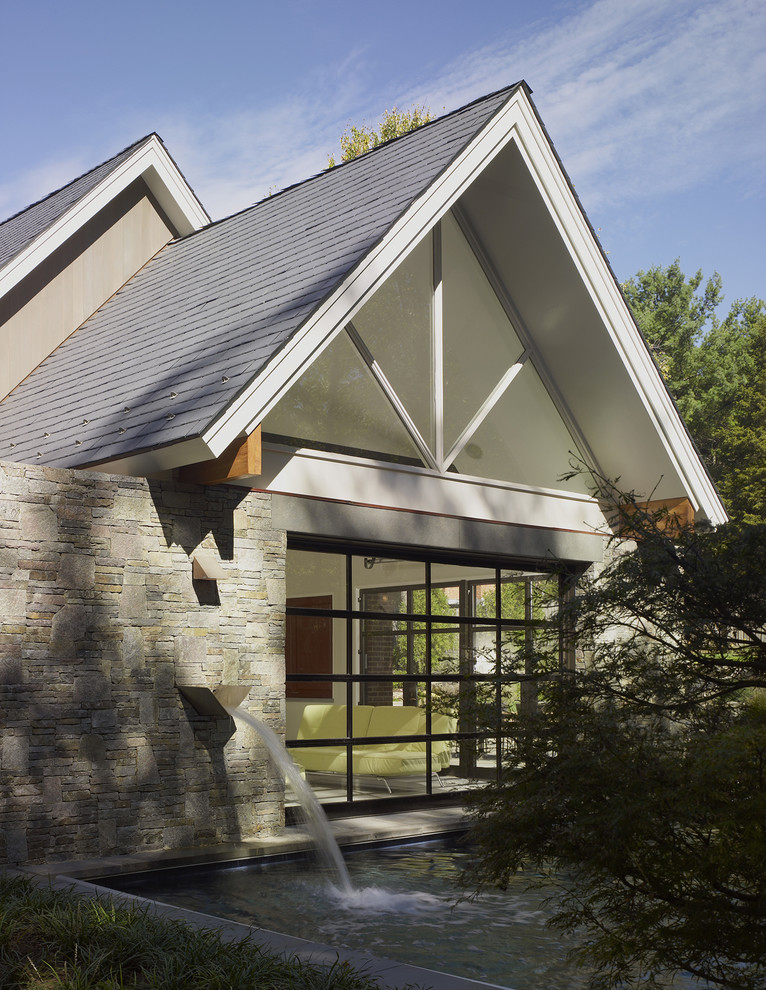 Small and gey contemporary bungalow house exterior in DC Metro with stone cladding and a pitched roof.
