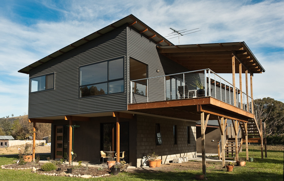 Diseño de fachada de casa gris de estilo americano grande de dos plantas con revestimiento de metal, tejado plano y tejado de metal