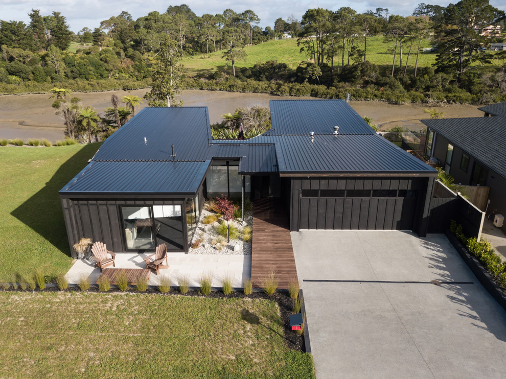 Inspiration pour une façade de maison noire design en bois de taille moyenne et de plain-pied avec un toit plat et un toit en métal.