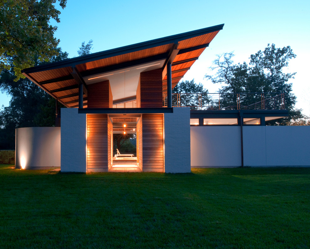Ejemplo de fachada minimalista de dos plantas con revestimientos combinados y tejado de un solo tendido