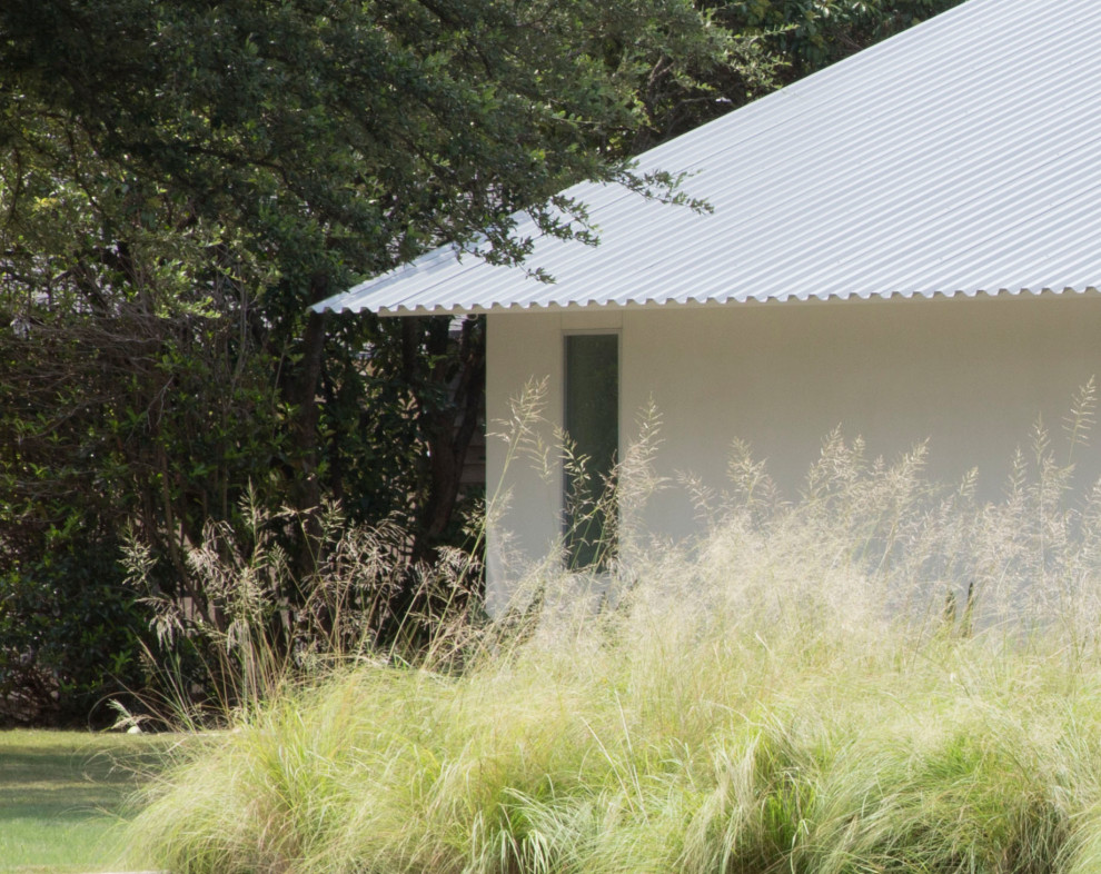 Diseño de fachada de casa blanca moderna de una planta con revestimiento de estuco y tejado de metal