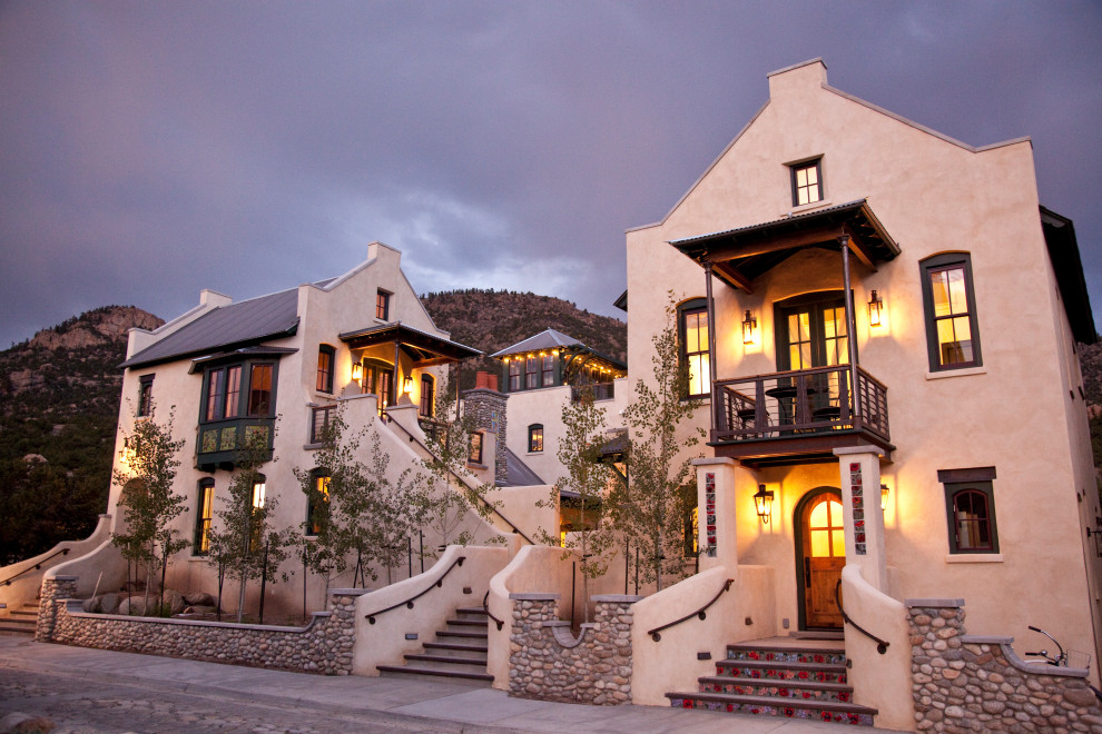 Foto della villa ampia beige mediterranea a tre piani con copertura in metallo o lamiera