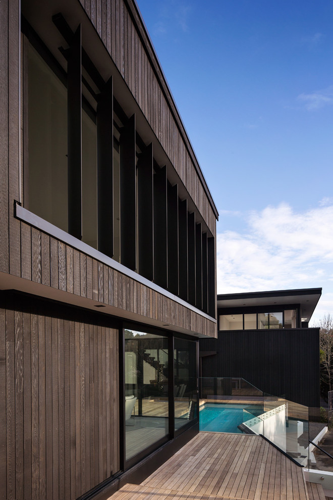 На фото: деревянный, двухэтажный, коричневый частный загородный дом среднего размера в стиле модернизм с плоской крышей и металлической крышей с