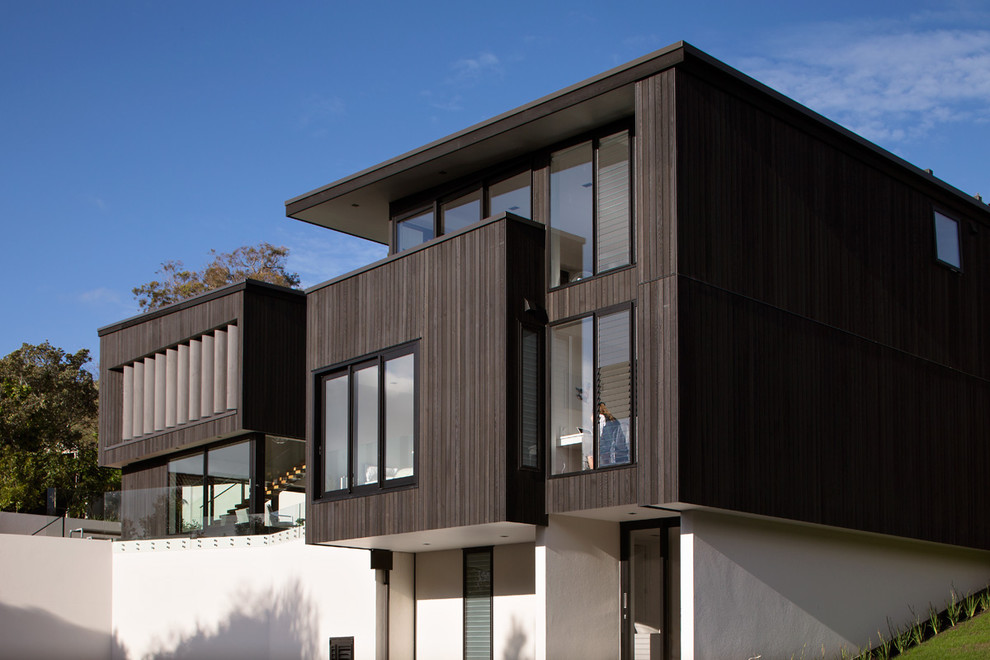 Réalisation d'une façade de maison marron minimaliste en bois à un étage et de taille moyenne avec un toit plat et un toit en métal.