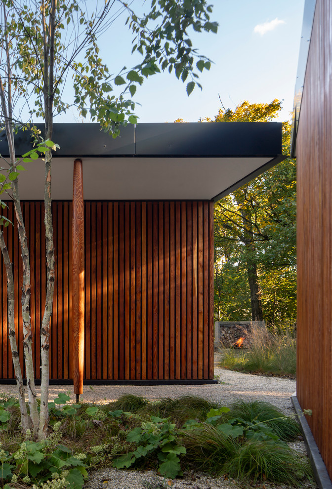 Cette image montre une façade de maison noire minimaliste en bois de plain-pied avec un toit plat.