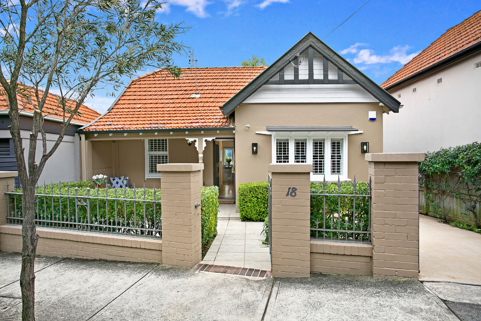 This is an example of a small and beige traditional bungalow brick house exterior in Sydney with a pitched roof.
