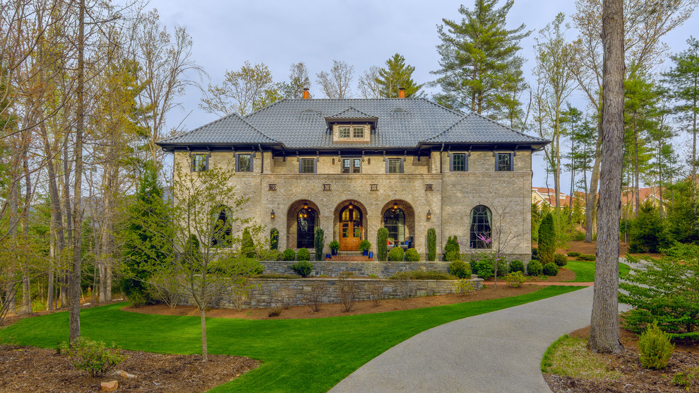 Foto della facciata di una casa beige classica a due piani con rivestimento in pietra e tetto a padiglione