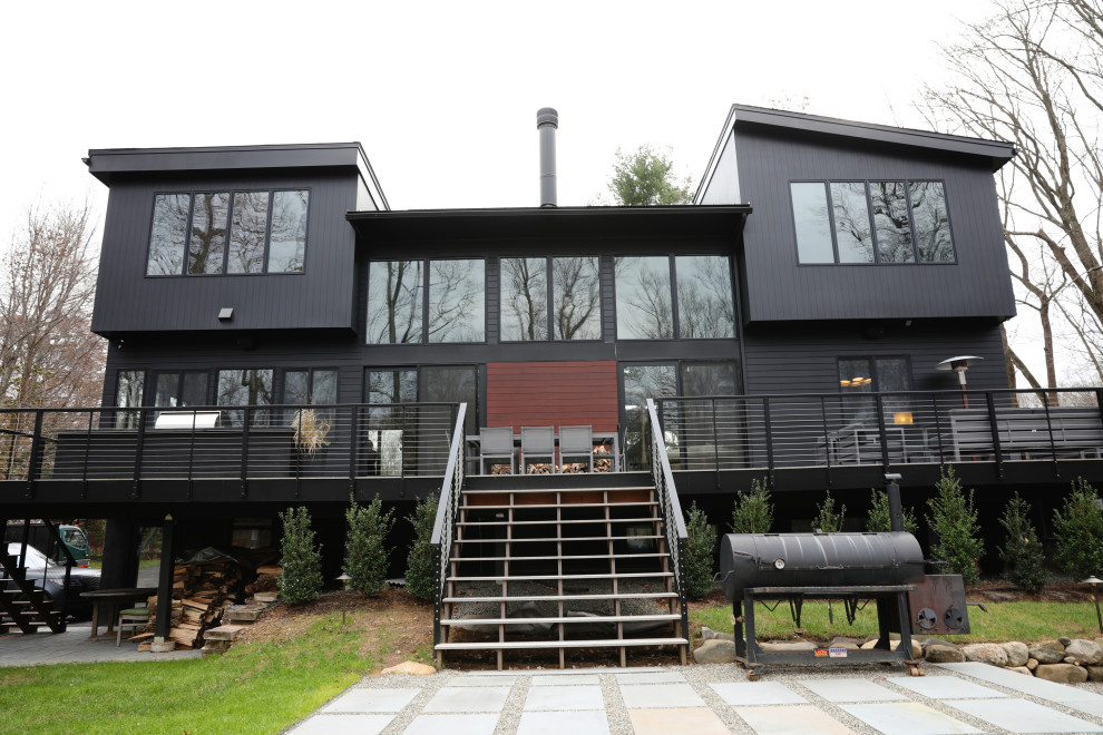 Diseño de fachada de casa negra actual de tamaño medio de dos plantas con revestimientos combinados, tejado de un solo tendido y tejado de metal