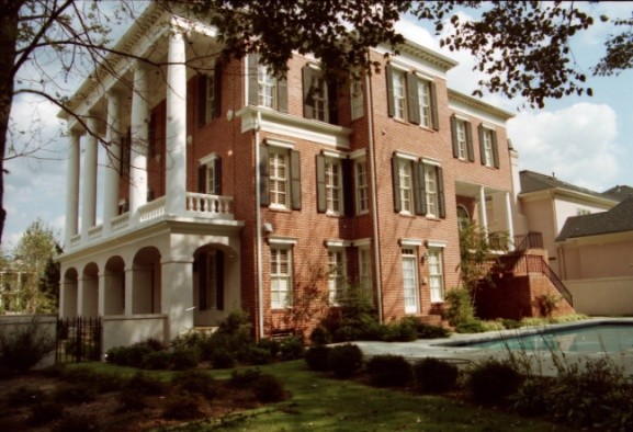 Large and red traditional brick house exterior in Atlanta with three floors and a flat roof.