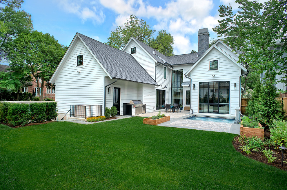 Mittelgroßes, Zweistöckiges Landhaus Einfamilienhaus mit Betonfassade, weißer Fassadenfarbe, Satteldach und Schindeldach in Chicago