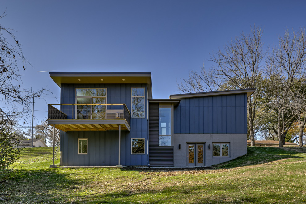 Diseño de fachada de casa azul retro de tamaño medio de dos plantas con revestimientos combinados, tejado de un solo tendido y tejado de metal