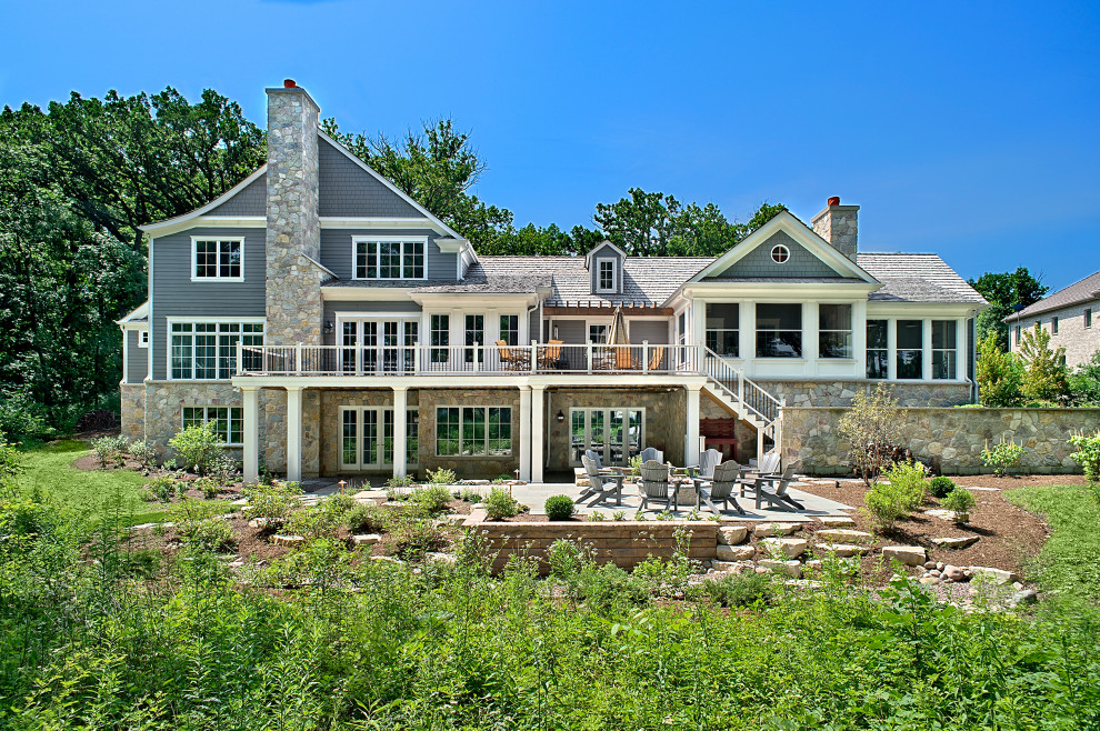 На фото: большой, двухэтажный, серый частный загородный дом в стиле неоклассика (современная классика) с облицовкой из камня, полувальмовой крышей и крышей из гибкой черепицы с