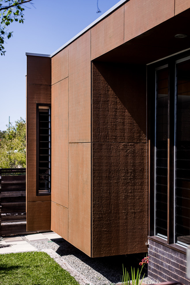 Foto de fachada marrón clásica renovada de tamaño medio de una planta con revestimiento de metal y tejado plano