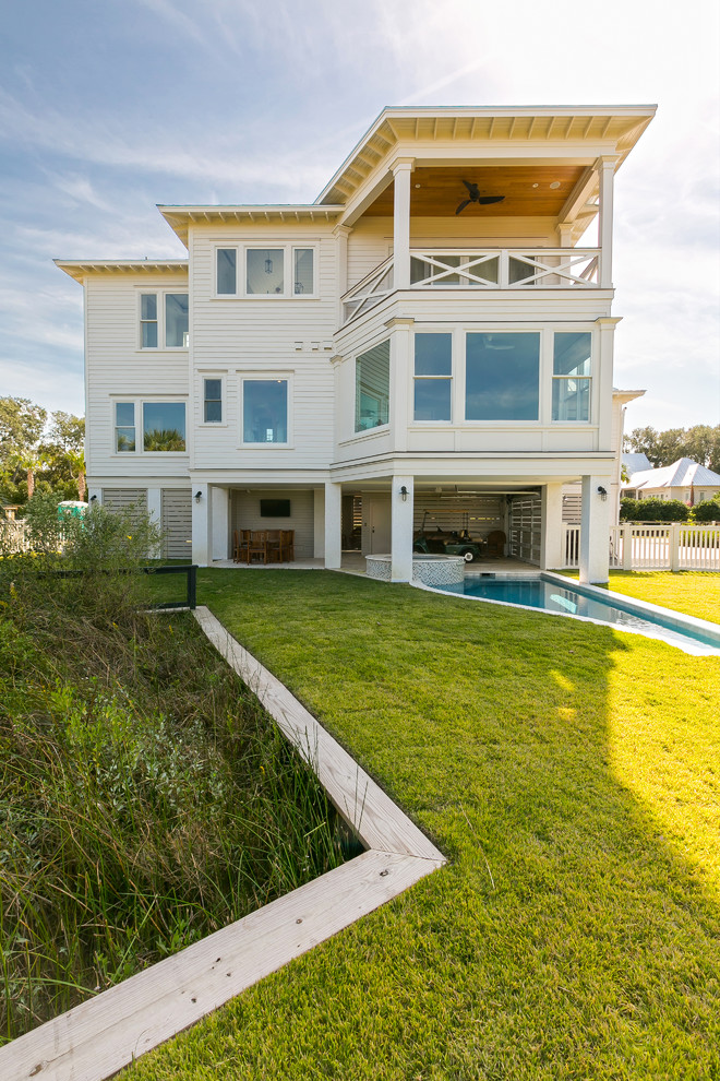 Cette image montre une petite façade de maison blanche marine en panneau de béton fibré à un étage avec un toit à quatre pans.