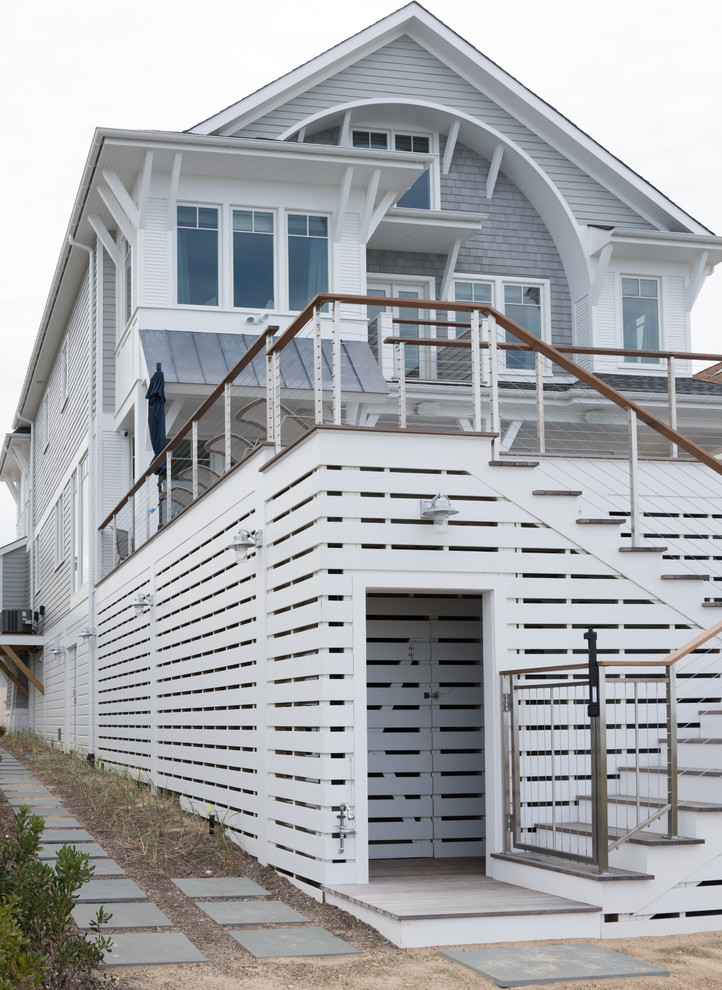 Modelo de fachada de casa gris costera de tamaño medio de tres plantas con revestimientos combinados, tejado a dos aguas y tejado de teja de madera