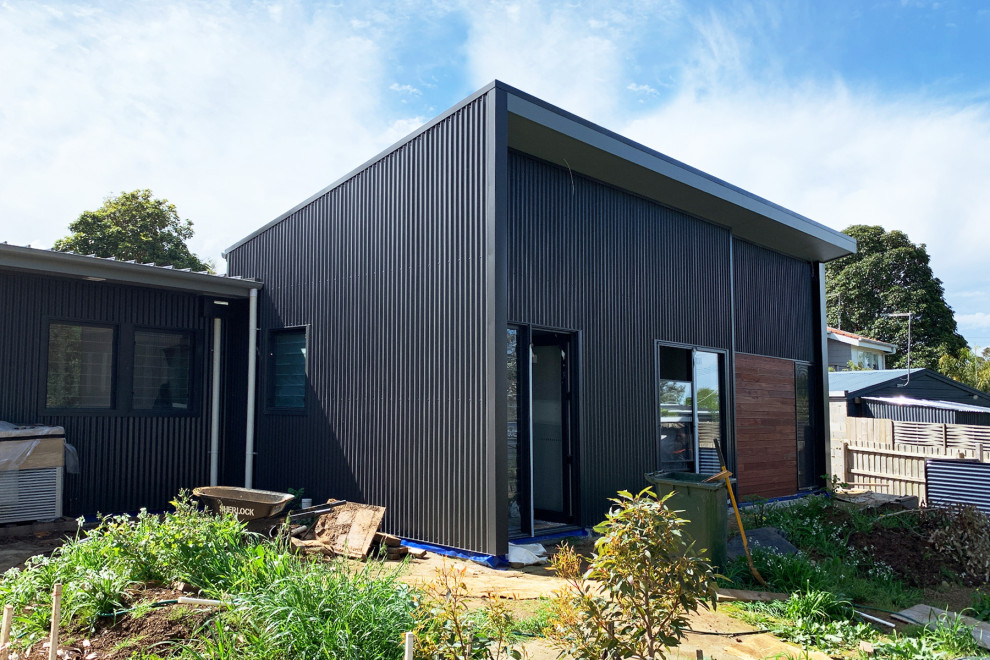 Modern inredning av ett mellanstort grått hus, med metallfasad, tak i metall och allt i ett plan