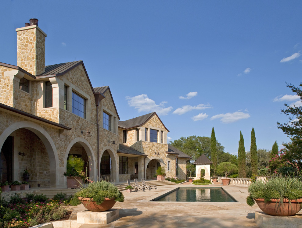 Expansive traditional two floor house exterior in Austin with stone cladding and a pitched roof.