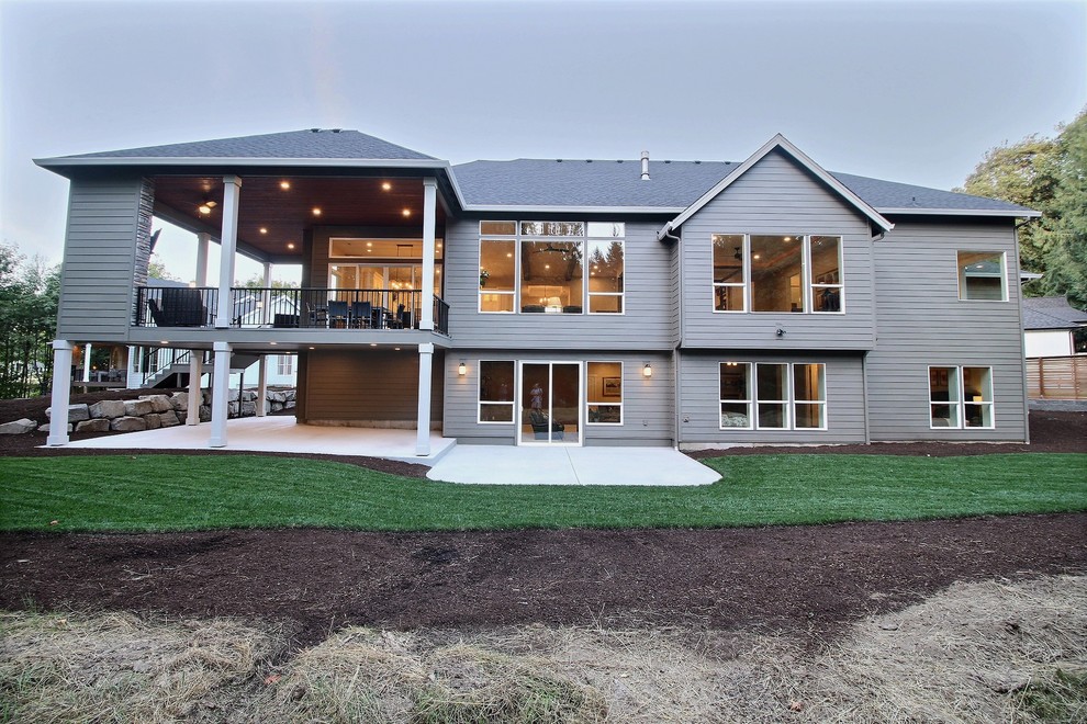 На фото: огромный, серый частный загородный дом в классическом стиле с разными уровнями, комбинированной облицовкой, двускатной крышей и крышей из гибкой черепицы