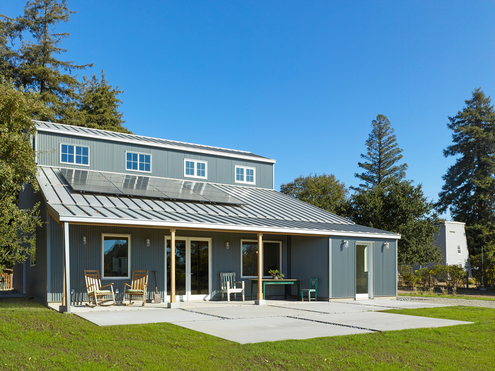 Réalisation d'une façade de maison métallique et grise champêtre à un étage avec un toit à deux pans et un toit en métal.