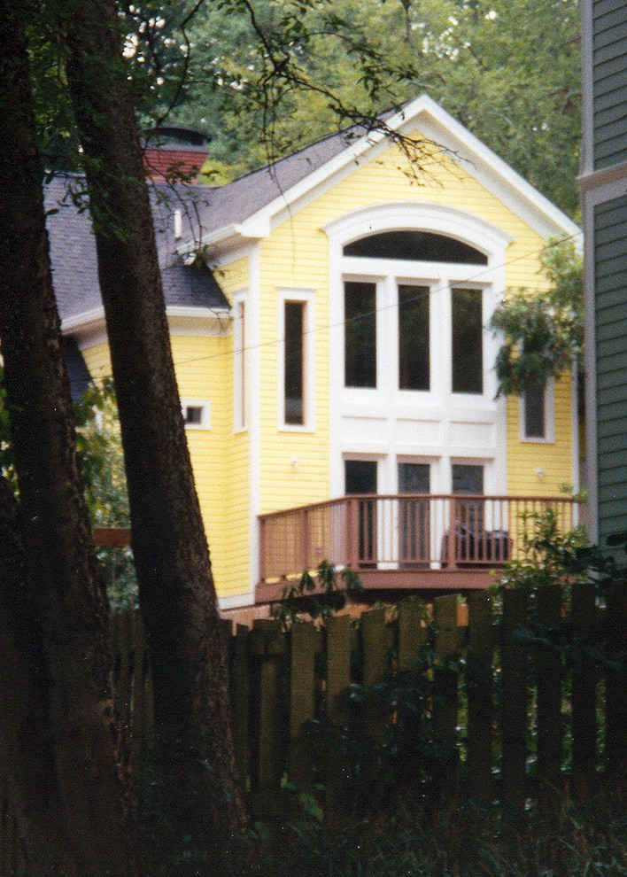 Стильный дизайн: двухэтажный, деревянный, желтый дом среднего размера в стиле кантри с двускатной крышей - последний тренд