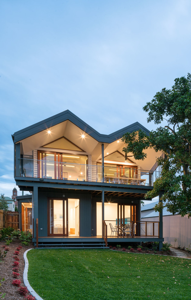 Cette image montre une façade de maison grise minimaliste à un étage avec un toit à deux pans.