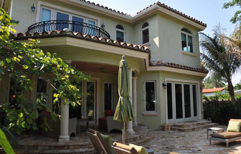 Diseño de fachada de casa beige mediterránea grande de dos plantas con revestimiento de estuco, tejado a cuatro aguas y tejado de teja de barro