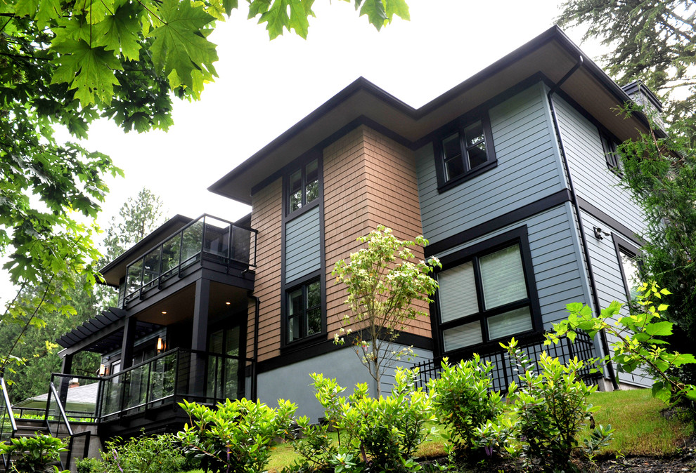 На фото: большой, двухэтажный, синий частный загородный дом в современном стиле с комбинированной облицовкой и вальмовой крышей с