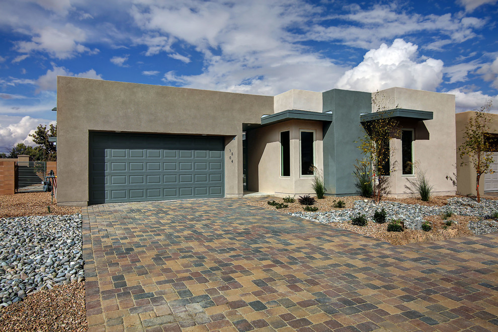Example of a mid-sized trendy beige one-story stucco flat roof design in Albuquerque