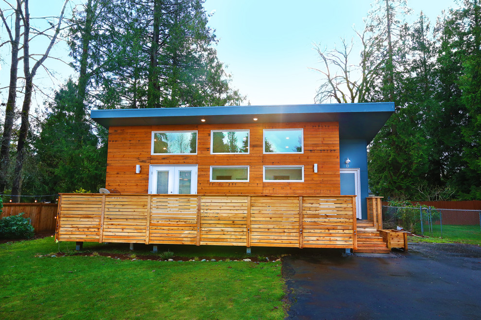 На фото: маленький, одноэтажный, синий частный загородный дом в скандинавском стиле с комбинированной облицовкой и односкатной крышей для на участке и в саду
