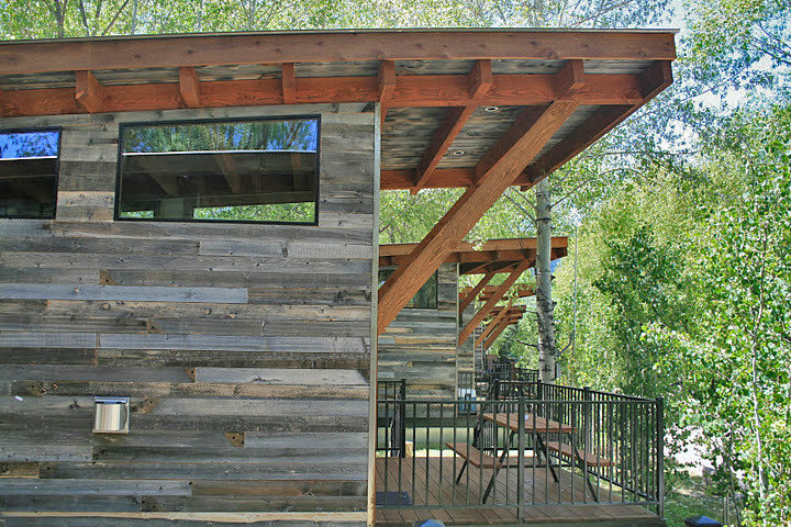 Cette photo montre une petite façade de maison grise moderne en bois de plain-pied avec un toit plat.
