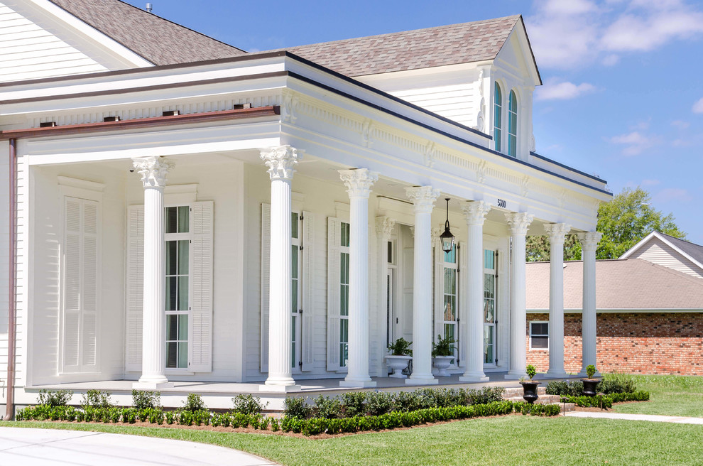 Foto della facciata di una casa grande bianca classica a due piani con rivestimento in legno e tetto a padiglione