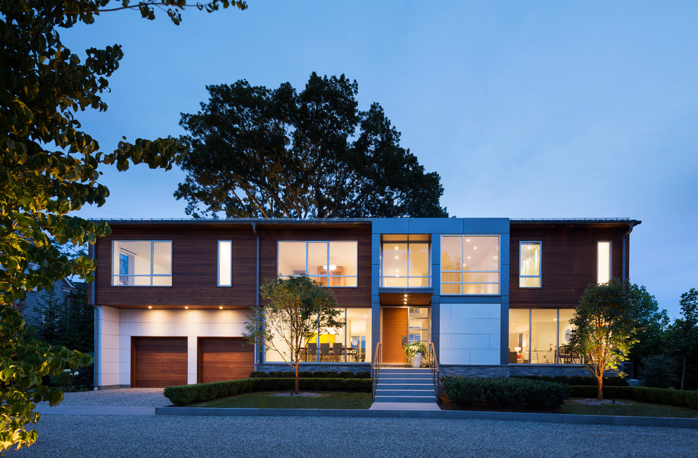 Réalisation d'une façade de maison design à un étage avec un toit à deux pans, un revêtement mixte et un toit en métal.