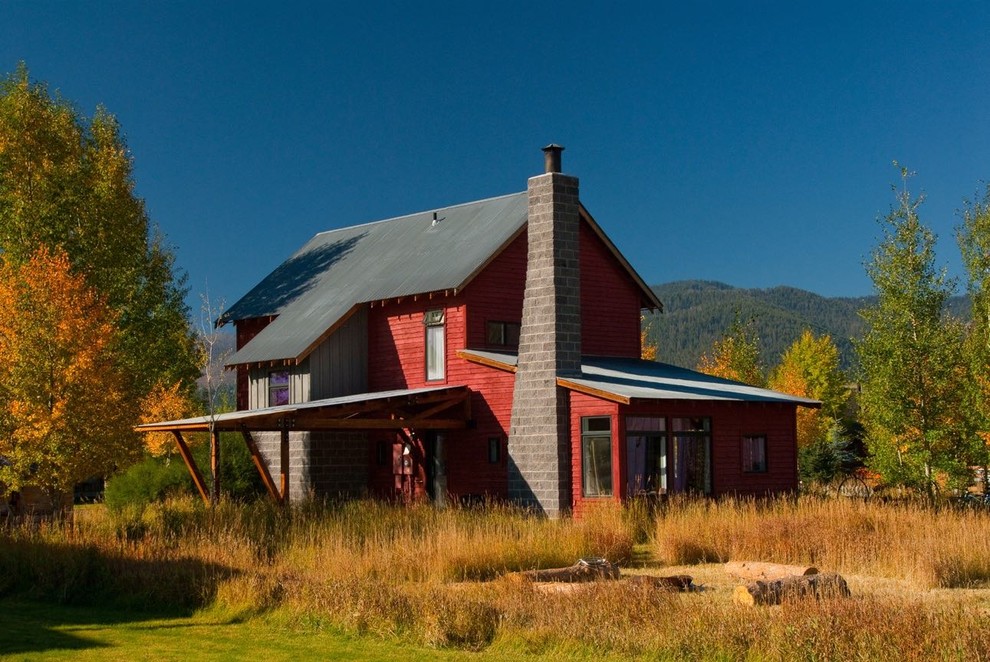 Cette image montre une façade de maison rouge chalet en bois de taille moyenne et à un étage avec un toit à deux pans.