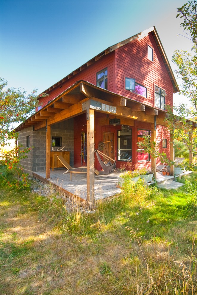 Aménagement d'une façade de maison rouge campagne en bois de taille moyenne et à un étage avec un toit à deux pans.