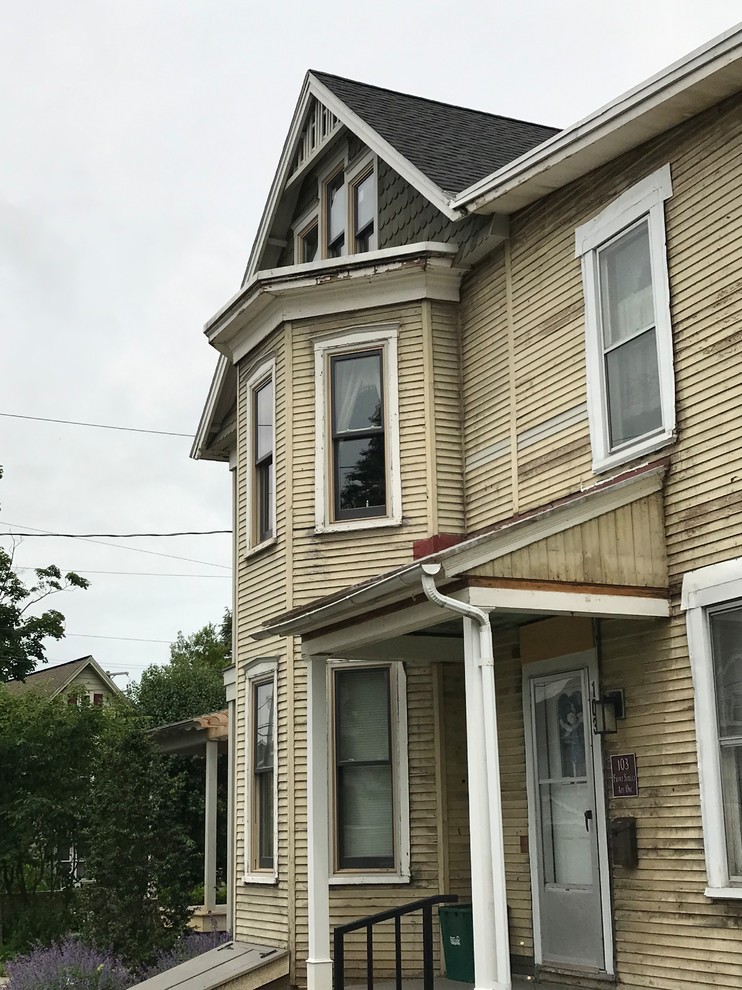Photo of a large victorian flat in Philadelphia with three floors, wood cladding, a pitched roof and a shingle roof.