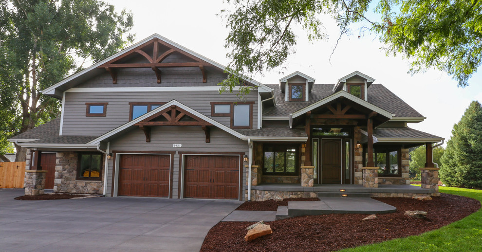 Diseño de fachada de casa gris campestre grande a niveles con revestimientos combinados, tejado a dos aguas y tejado de teja de madera