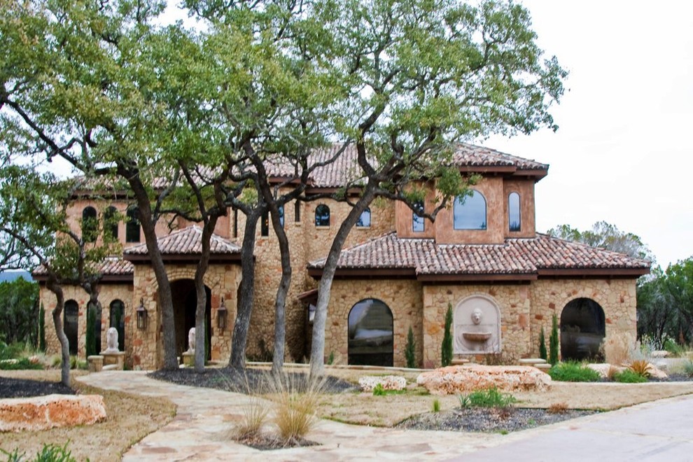 Photo of a large and beige mediterranean two floor house exterior in Austin with stone cladding.