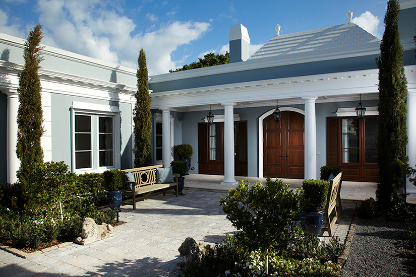 Diseño de fachada azul clásica renovada grande de una planta con revestimiento de estuco y tejado plano