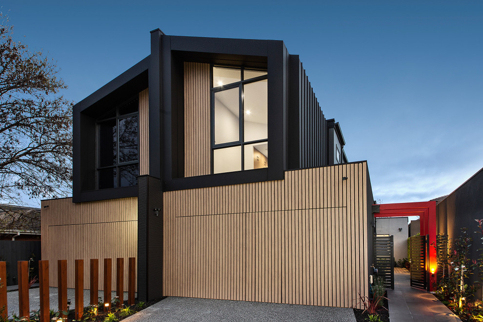 Diseño de fachada de casa bifamiliar negra actual grande de dos plantas con revestimientos combinados y tejado de metal