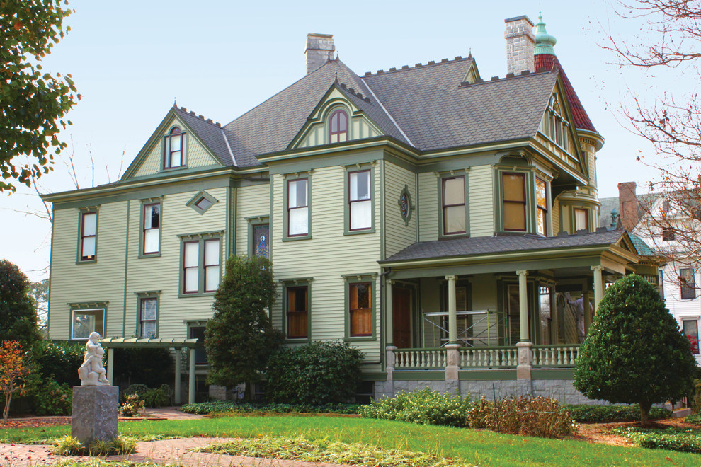 Aménagement d'une grande façade de maison verte victorienne en bois à deux étages et plus avec un toit à quatre pans et un toit en tuile.